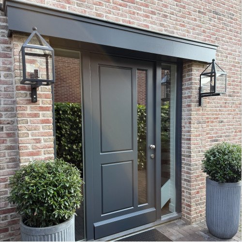 applique d'extérieur noire avec boîtier en acier inoxydable, verre clair, ampoule visible dans le luminaire, forme maisons 